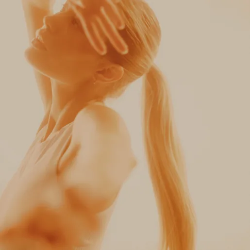 Woman in light with hand over face